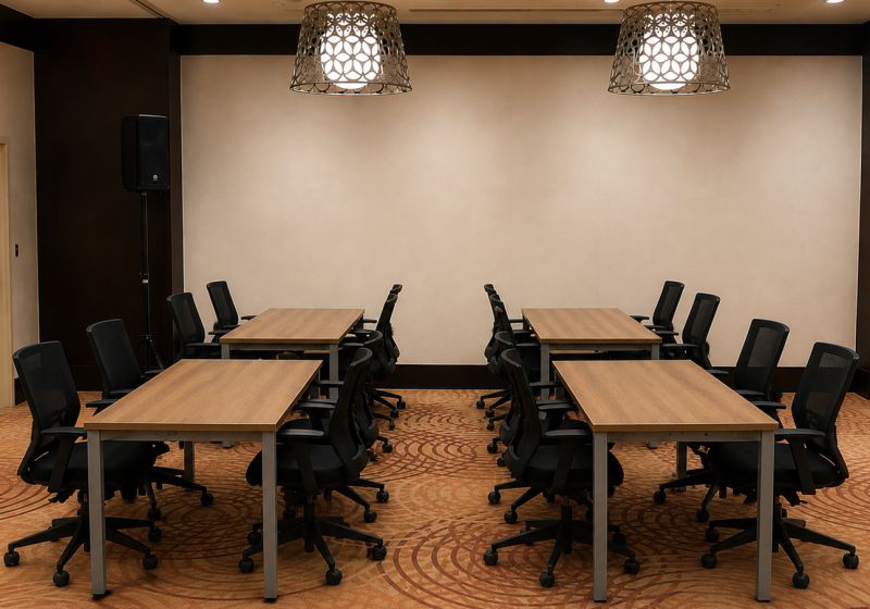 Classroom-style meeting room with wooden tables and black office chairs