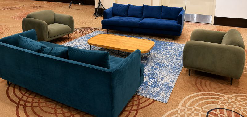Velvet sofas and green armchairs around a wooden coffee table in a lounge setting